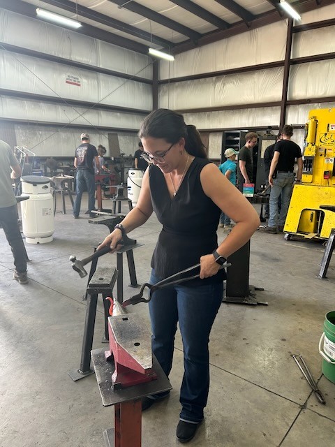 A student learning blacksmithing with hammer and tongs at Kilroy’s Workshop.
