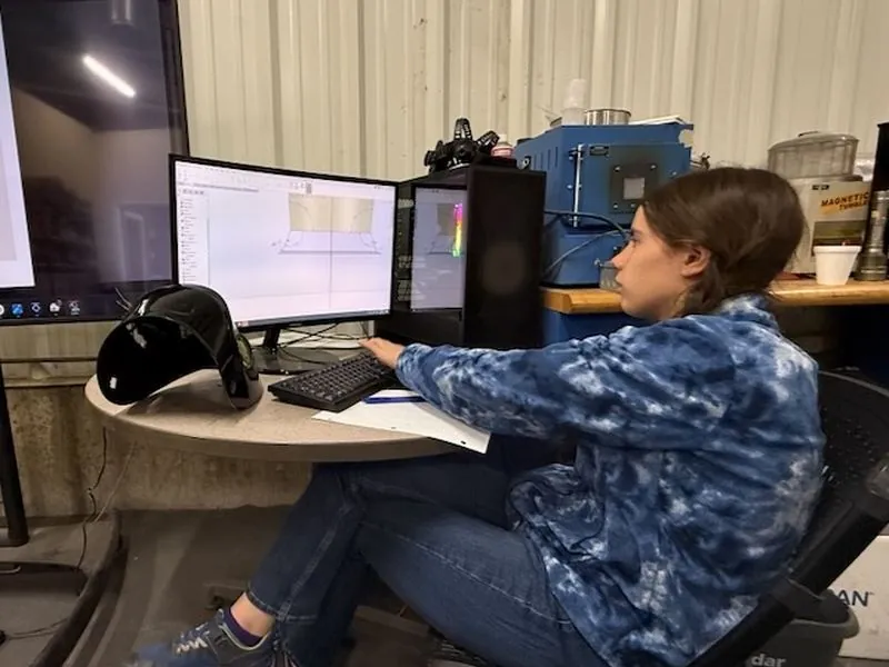 A student designing a part in CAD at a dual-monitor workstation.
