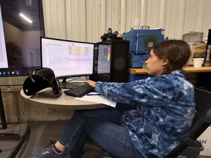 A student designing a part in CAD at a dual-monitor workstation.