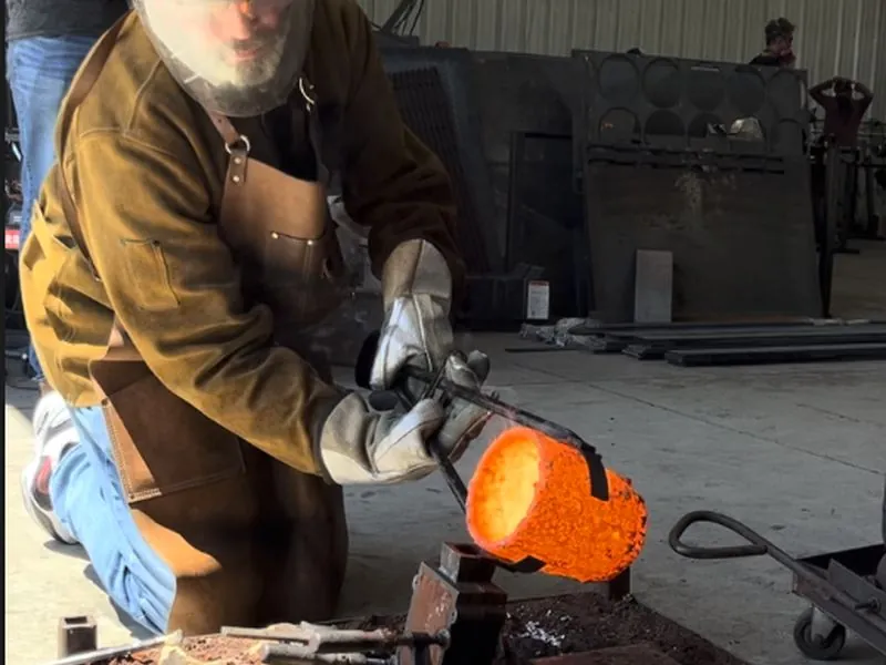 Pouring glowing molten metal from a crucible into a mold.